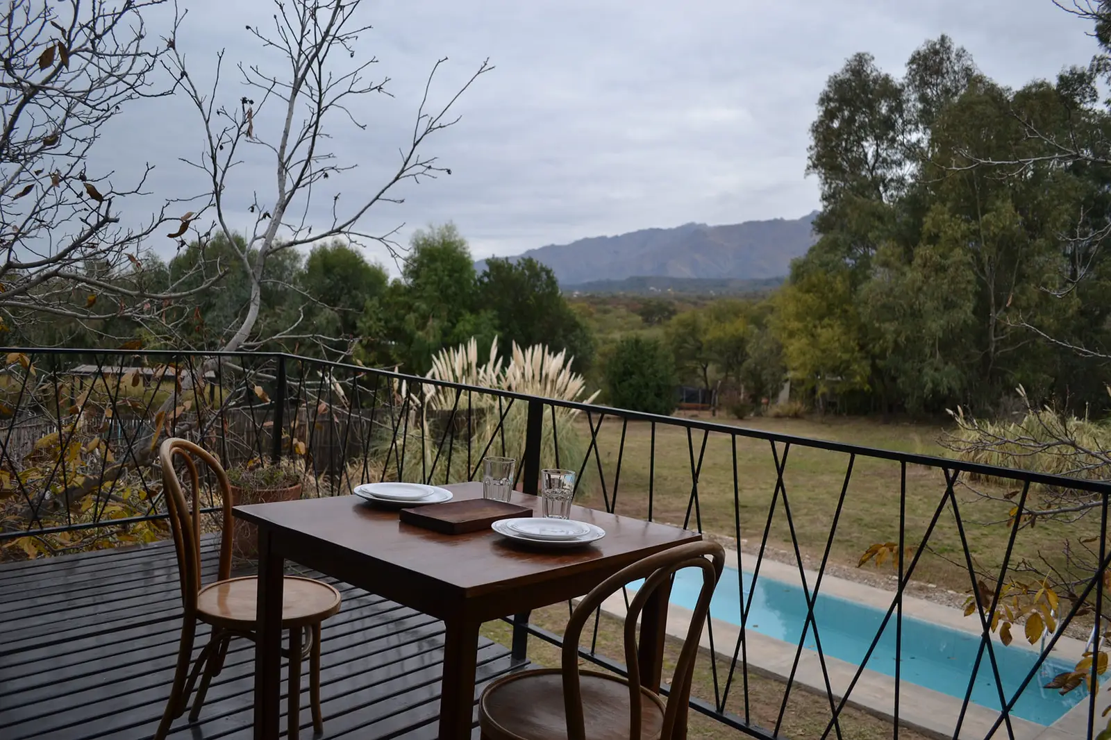 Balcón con mesa y vista a la pileta y las sierras