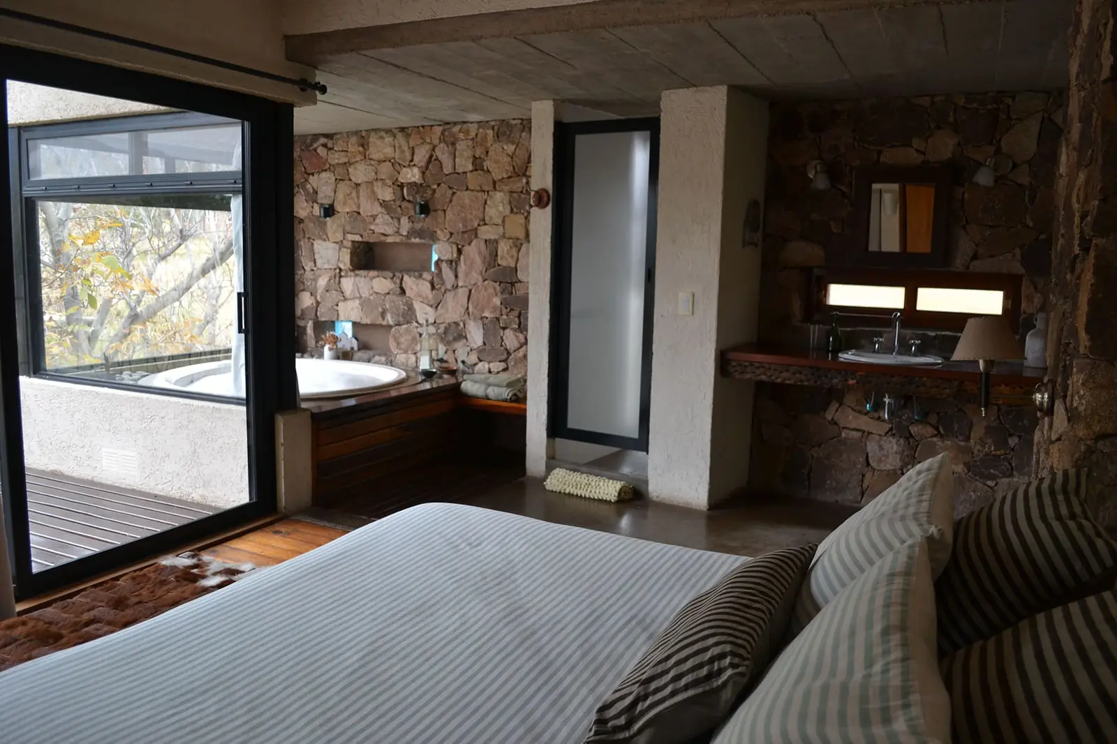 Dormitorio en suite con jacuzzi y paredes de piedra