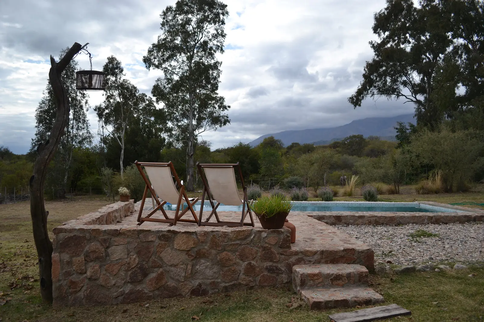 Solárium de piedra con reposeras junto a la pileta de Casa Lavanda
