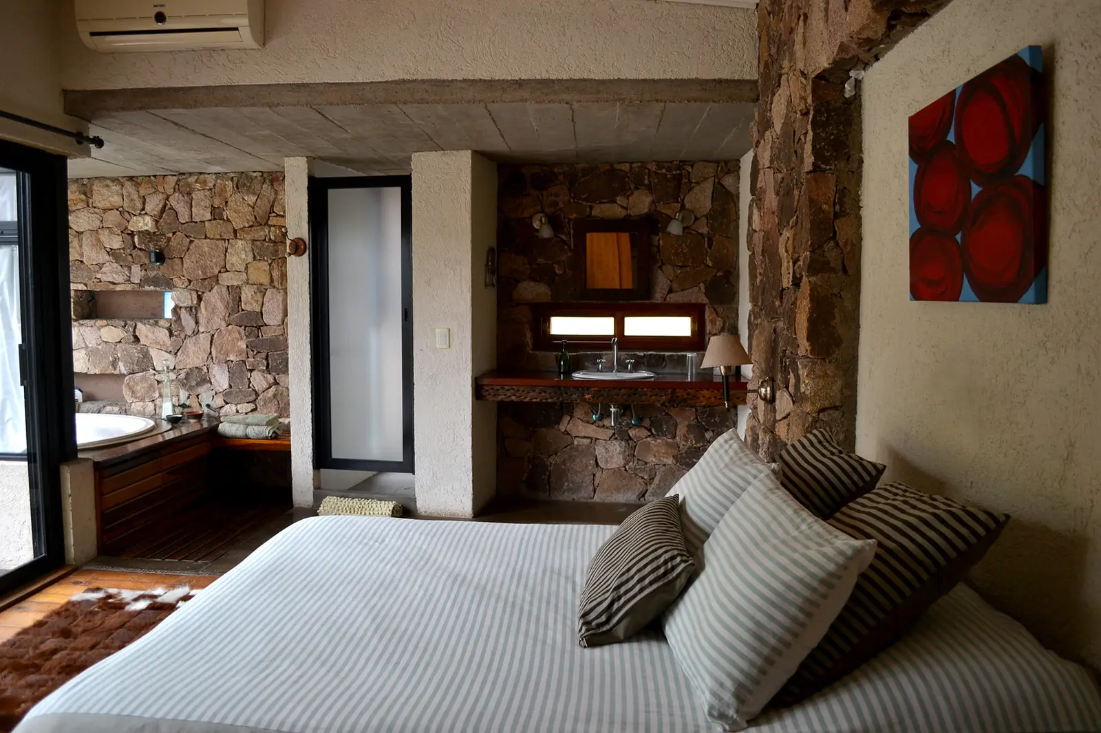 Dormitorio en suite con jacuzzi y paredes de piedra